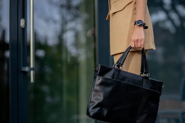 Business lady holding a laptop bag going to the office. Display of businesswoman on modern buildings in the city.