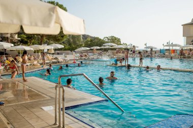 Güzel bir manzarası olan havuz manzarası. Oteldeki açık havuzun etrafında şemsiye ve koltuk var. 28 Haziran 2022, Türkiye