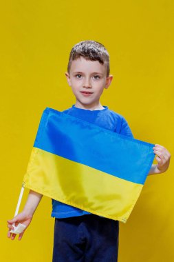 Ukrayna 'nın sarı ve mavi bayrağını tutan küçük çocuk gülümsüyor. Ukraynalı çocuk. Ukrayna 'nın Bağımsızlık Günü. Bayrak Günü.