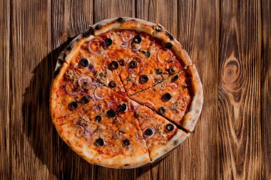 Pizza with tuna, olives, onions, mozzarella cheese and tomato sauce on wood background. Top view, copy space.