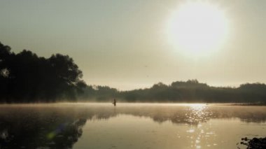 Fisherman pulling fish on the river in a foggy summer morning. Fishing for spinning.