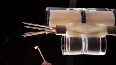 A woman's hand lights scented candles with a match. Romantic dinner. On a dark background. Vertical video