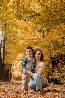 Portrait of Mother and son walking outdoors on a sunny autumn day. The family is dressed in autumn clothes. Happy together.