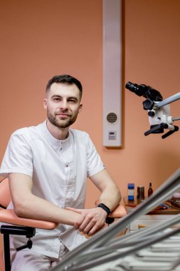 Erkek bir dişçi mikroskoba bakar. Yeni teknolojiler kullanan modern dişçilik.