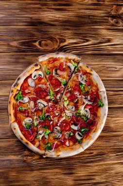 Vegan pizza with tomato sauce, cherry tomatoes, mushrooms, broccoli, red onion on wodenbackground. View from above.
