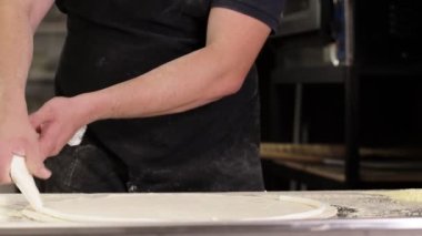 The chef's hands wrap the cheese rim in the raw pizza dough. Making pizza with cheese side.