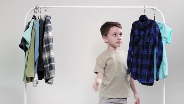 ハンガーのそばに立つ男の子の未就学児 衣類を積み上げ そして今日のために服を選ぶ — ストック動画