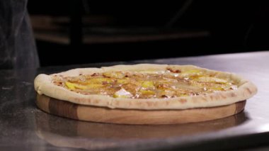 Adding melted chocolate to a sweet pizza on a creamy base with apples, cinnamon, mozzarella cheese. Presentation of sweet pizza.