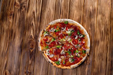Vegan pizza with tomato sauce, cherry tomatoes, mushrooms, broccoli, red onion on wodenbackground. View from above.