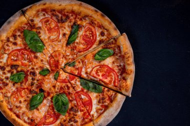 Nefis kokulu pizza, mozzarella, domates ve siyah arka planda domates soslu fesleğen..