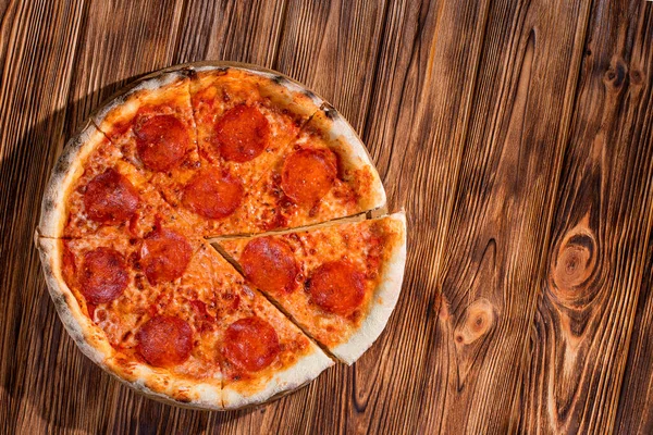 Domates soslu pizza, mozzarella, ahşap arka planda salam. Yukarıdan görüntüle, boşluğu kopyala.