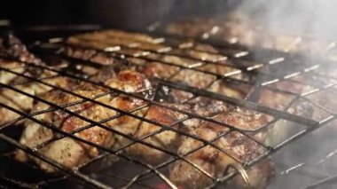 Outdoor barbecue picnic cooking process, grilling and grilling juicy meat steaks with burning fire and smoke on barbecue grill, burning coals. Barbecue grill concept.