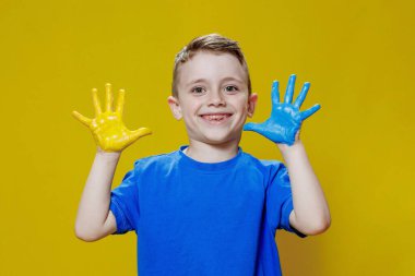 Avuç içleri sarı ve maviye boyanmış, Ukrayna bayrağı renginde küçük mutlu bir çocuk. Ukraynalı yaratıcı anaokulu öğrencisi.