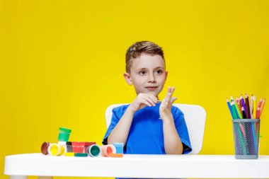 Küçük bir anaokulu öğrencisi elinde fırçayla masada oturur ve avucunu boyar. Anaokulu geliştirme