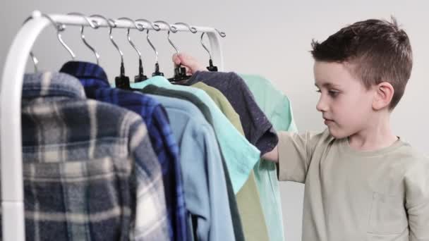 Хлопчик Дошкільник Стоїть Біля Вішалок Піднімає Одяг Вибирає Одяг Сьогоднішній — стокове відео