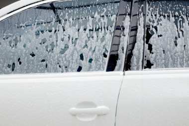 Aktif köpüklü beyaz bir arabada ayna yıkamak. Araba yıkama.