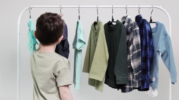 男孩子们站在衣架旁边 把衣服叠起来 为今天挑选衣服 — 图库视频影像