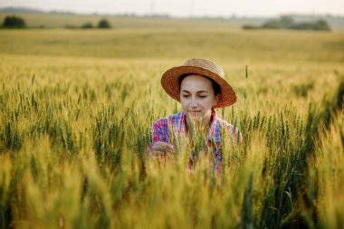 Genç bir çiftçi buğday başağında oturur ve burada büyümeyi analiz eder..