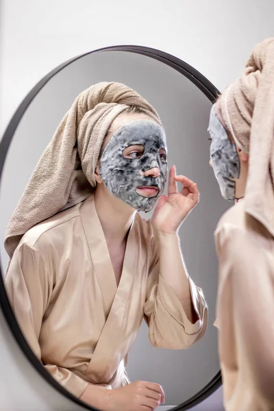 Ung Lycklig Kvinna Handduk Gör Ansiktsmask Och Tittar Spegel Elegant — Stockfoto