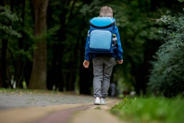 Sırt çantalı küçük çocuk okula gidiyor. Dikiz aynası. Birinci sınıf öğrencisi.