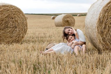 Genç anne ve oğlu bir tarlada saman balyalarının yanında sarılıyorlar. Mutlu bir aile. Anneler Günü..