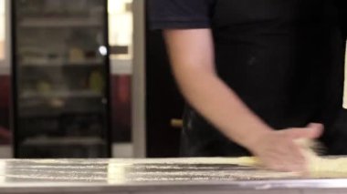 İtalyan bir aşçının elinde çiğ hamur profesyonel bir mutfakta İtalyan pizzası yapmak için un ile hamur hazırlıyor.