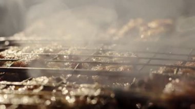 Outdoor barbecue picnic cooking process, grilling and grilling juicy meat steaks with burning fire and smoke on barbecue grill, burning coals. Barbecue grill concept.