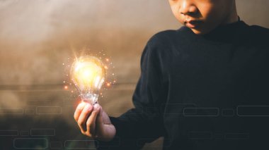 Dört yaşında elinde ampul tutan bir çocuk. Yenilik. Yenilik ve ilham ile yeni bir fikir kavramı, bilim ve iletişim kavramında yenilikçi teknoloji kavramı için el ele tutuşmak, 