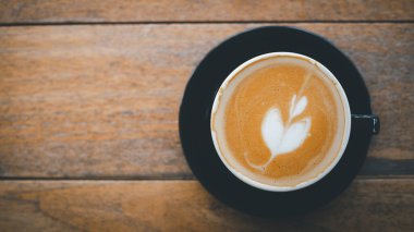 Tahta arkaplandaki latte kahvenin üst görüntüsü kahve suratındaki desen mükemmel değil. kopyalama alanı ile