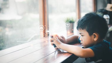 Yakışıklı Asyalı adam evde cam pencerenin yanında oturuyor ve evinde cep telefonu var. Büyük bir coşkuyla çeşitli medyayı kullanarak ciddi bir görünüm sergiliyorlar. Çevrimiçi eğitim, evde eğitim.