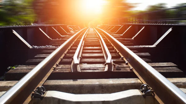 Railroad in motion at sunset. Railway station with motion blur effect against colorful blue sky, Industrial concept background. Railroad travel, railway tourism. Blurred railway. Transportation