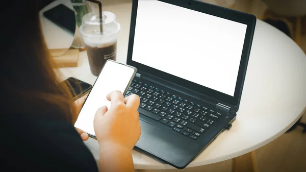 woman sitting and working with a notebook computer and use a mobile phone business woman concept along with the phone screen clipping path and the notebook screen