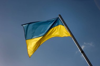 Mavi gökyüzüne karşı Ukrayna bayrağı sallayarak.
