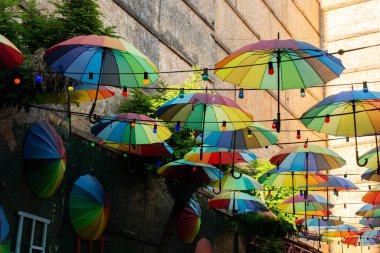 Şemsiyeler sokağın üzerinde yüzüyor güneş ışığından korunuyor