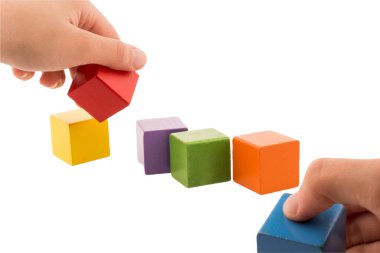 Renkli tahta bloklarla oynayan ve inşa eden eller. Erken öğrenme ve geliştirme