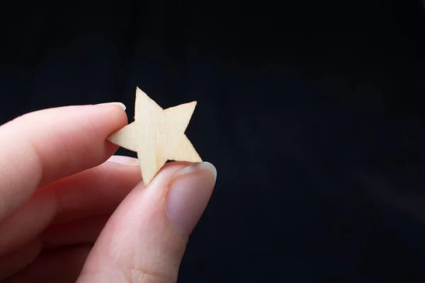 The hand holding a  wooden star.