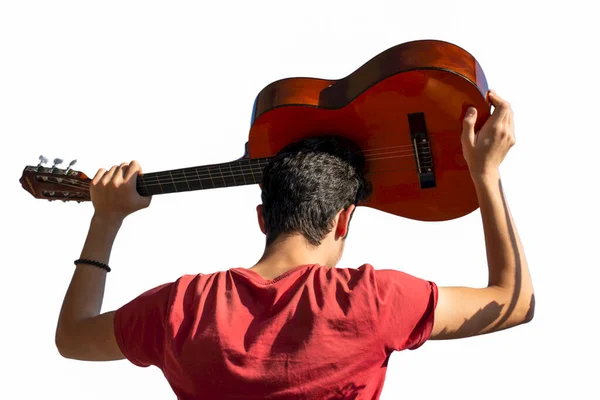 Young man rising an accoustic guitar in the blue sky