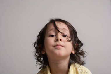 Küçük şirin çocuk ciddi bir yüz ifadesi takınmaya çalışıyor.