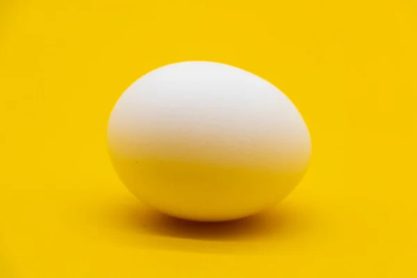 在黄色背景下分离的单个白色鸡蛋 — 图库照片