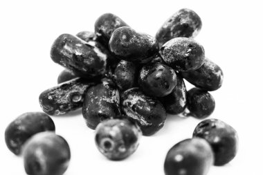 Düşük ışıkta beyaz zemin üzerinde izole edilmiş siyah üzümler.