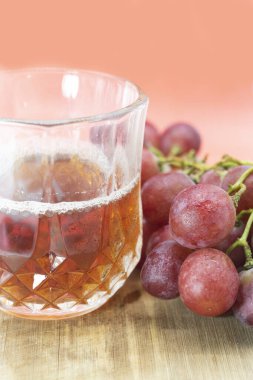 Ahşap arka planda izole edilmiş üzümlü bir kadeh kırmızı şarap.