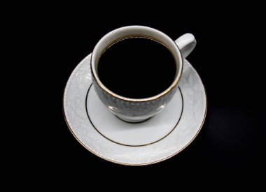 Siyah arka planda çay dolu antik çay fincanı.