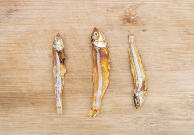 Kurutulmuş küçük balık ya da ançüez balığı ahşap arka planda izole edilir.,