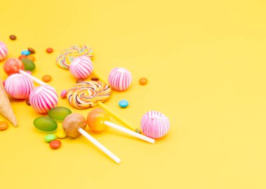 Sarı arkaplanda izole edilmiş renkli farklı şeker türleri