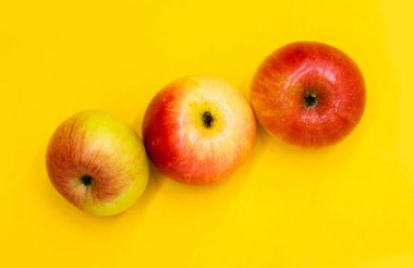 Kırmızı elma ve su damlası sarı arkaplanda izole edilmiş..