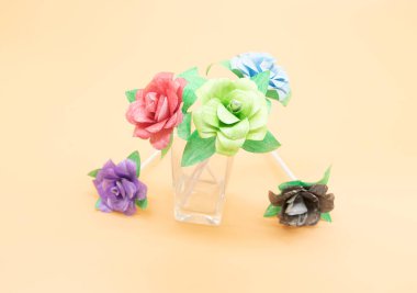paper made rose in different color isolate on colorful background