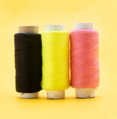 sarı, pembe ve siyah renk ipliği veya sarı arkaplanda makaralı iplik