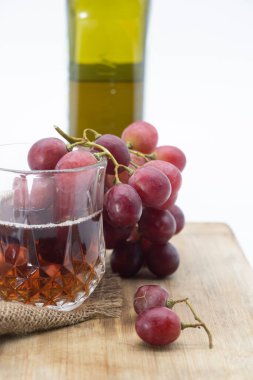 Bir bardak şarap ve şarap şişesi, ahşap arka planda izole edilmiş üzümler.,