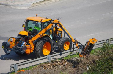Yol kenarı bakım ve hidrolik kollu bir traktör.