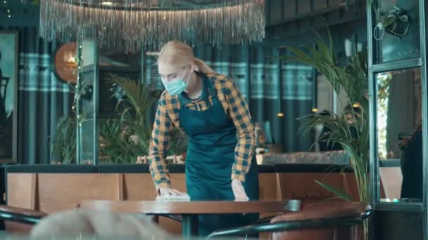 Mladá servírka má na sobě masku při uklízení — Stock video